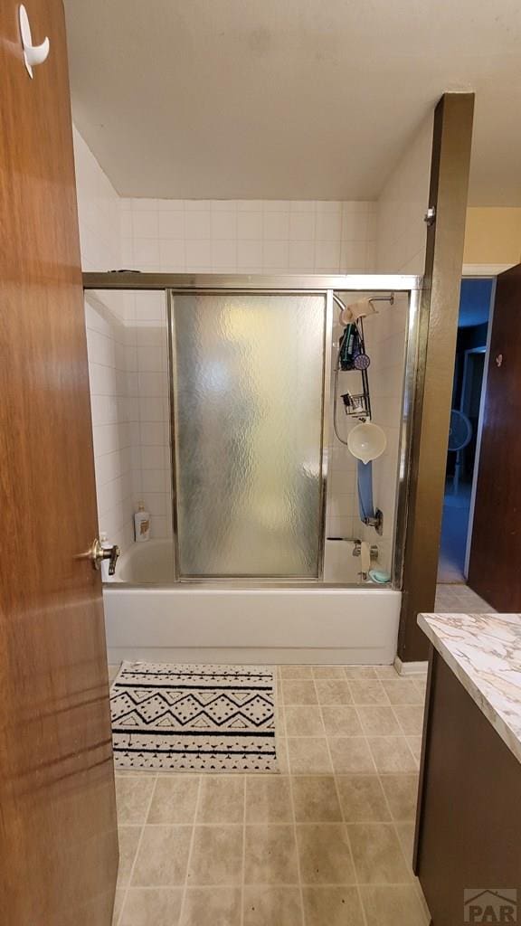 bathroom with combined bath / shower with glass door, tile patterned flooring, and vanity