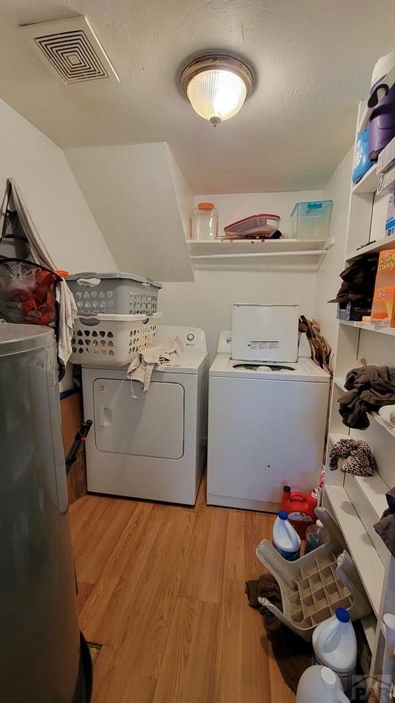 laundry room with laundry area, washing machine and clothes dryer, visible vents, and light wood-style floors