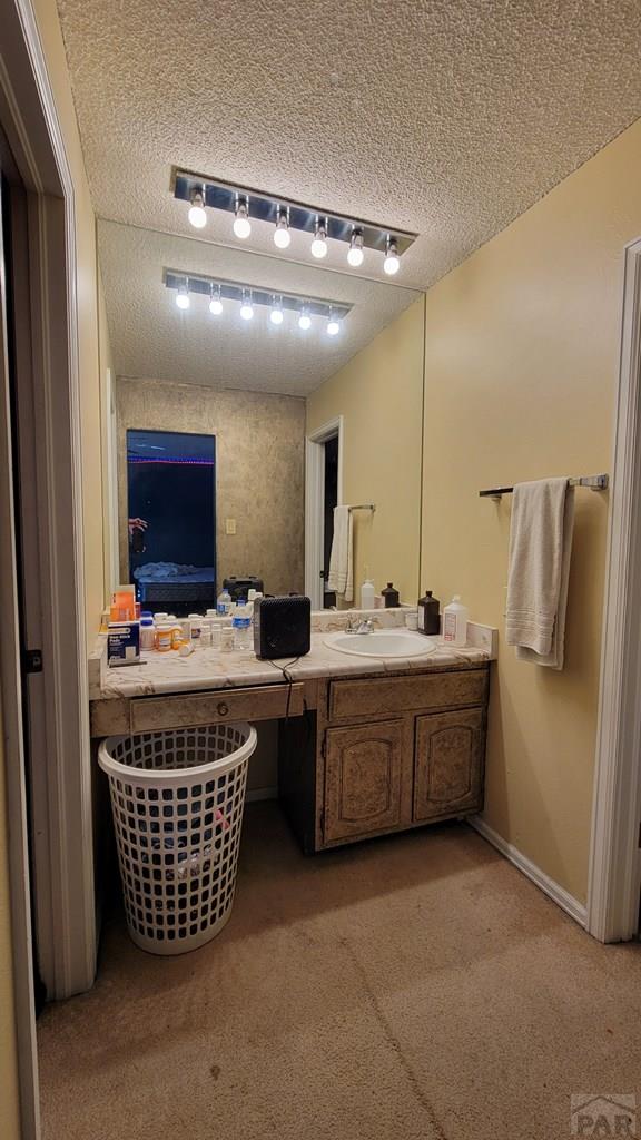 bathroom featuring track lighting, baseboards, a textured ceiling, and vanity