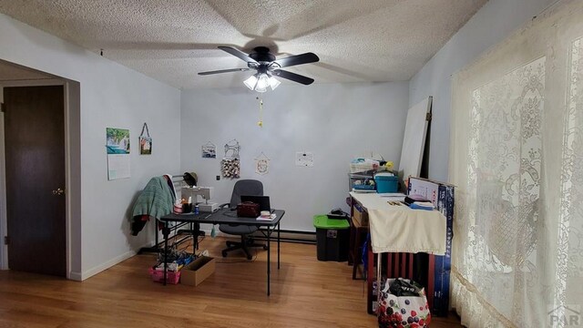 office area with ceiling fan, a textured ceiling, baseboard heating, and wood finished floors