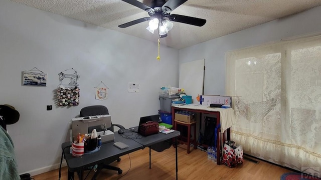 office area featuring ceiling fan, a textured ceiling, baseboards, and wood finished floors