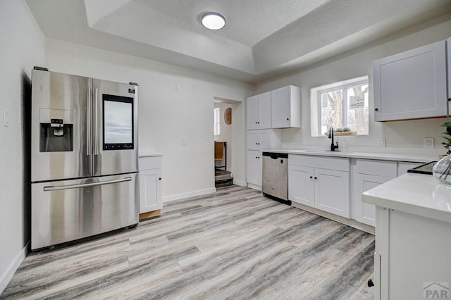 kitchen with white cabinets, a sink, stainless steel appliances, and light countertops
