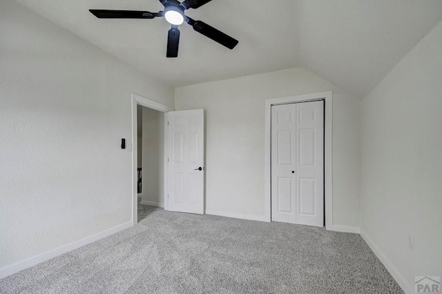 unfurnished bedroom featuring carpet floors, lofted ceiling, a closet, and baseboards