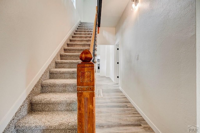 stairway with baseboards and wood finished floors