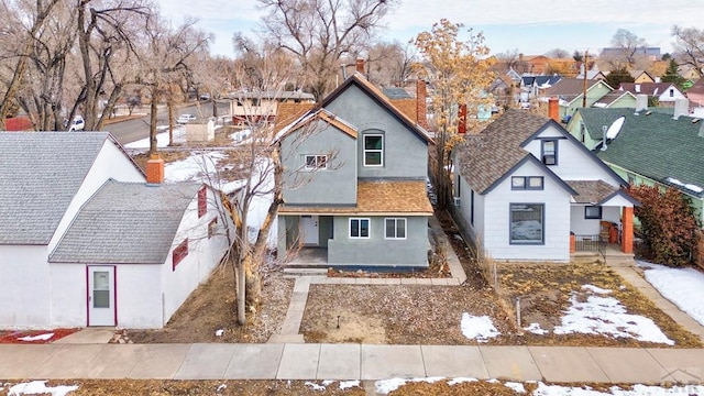 view of front of home with a shingled roof, a residential view, and stucco siding