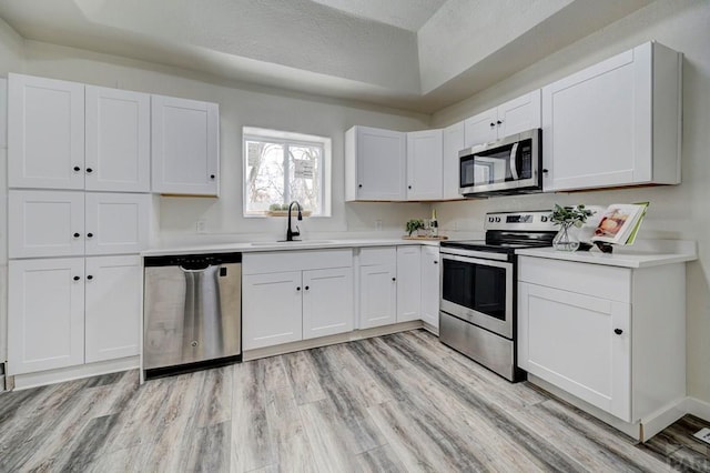 kitchen featuring stainless steel appliances, white cabinets, and light countertops