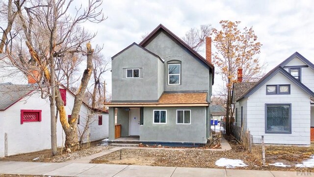 view of front of property featuring roof with shingles, a chimney, and stucco siding