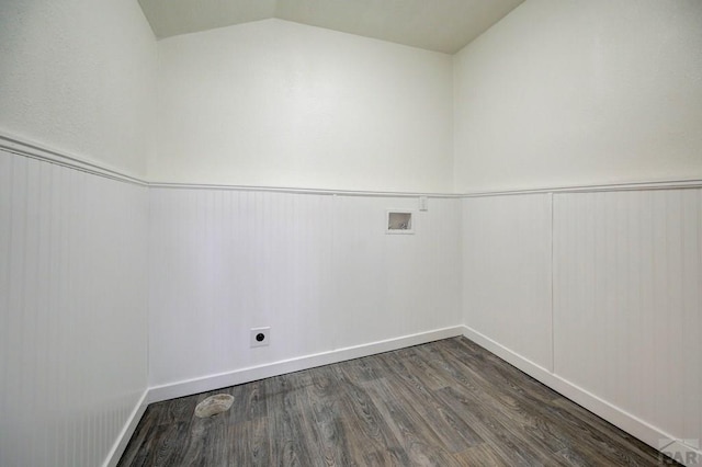 spare room featuring dark wood-type flooring, lofted ceiling, and a wainscoted wall