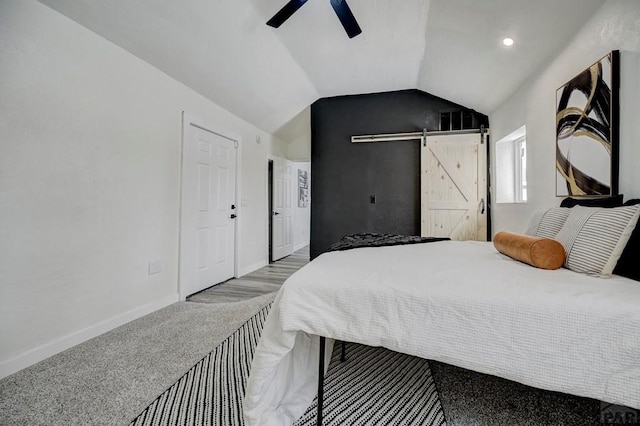 bedroom with lofted ceiling, a barn door, light carpet, ceiling fan, and baseboards