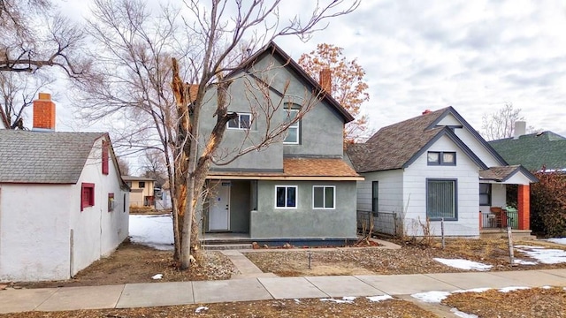 view of front of house with a shingled roof, a porch, and stucco siding