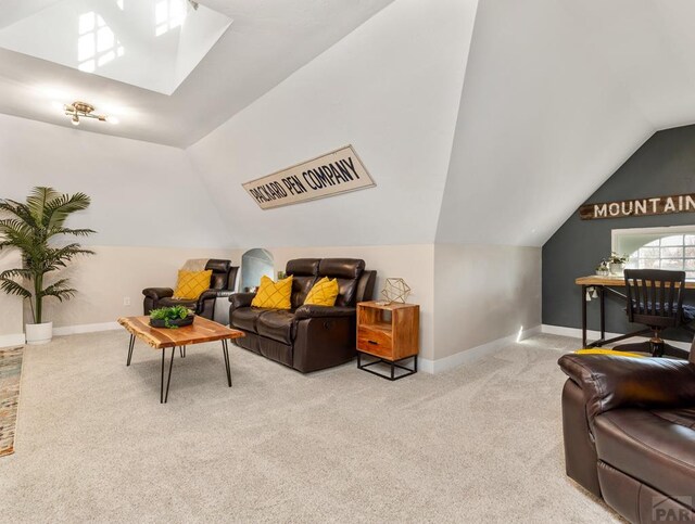 living room with lofted ceiling with skylight, baseboards, and light colored carpet