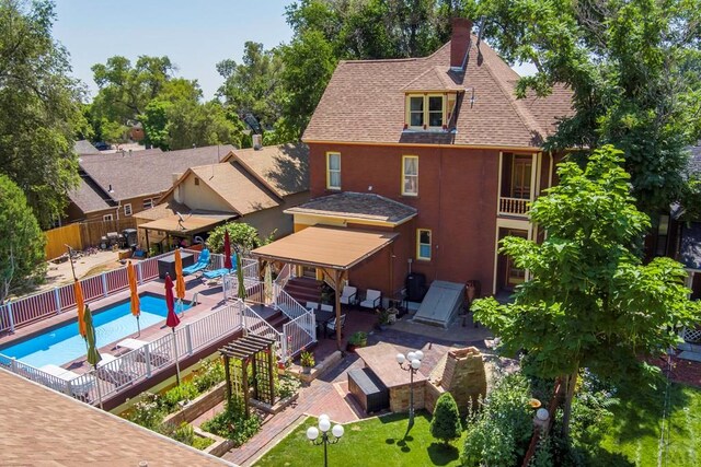 exterior space with a patio area, a shingled roof, fence, and a fenced in pool