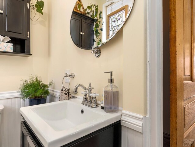 bathroom with vanity, a decorative wall, and wainscoting