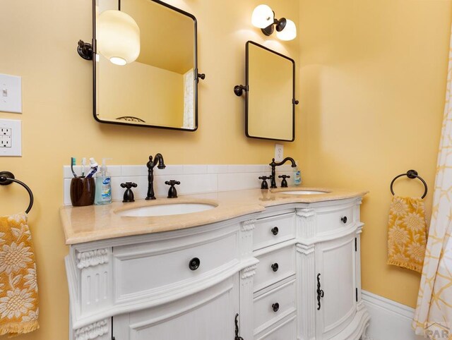 full bathroom with a sink, baseboards, and double vanity