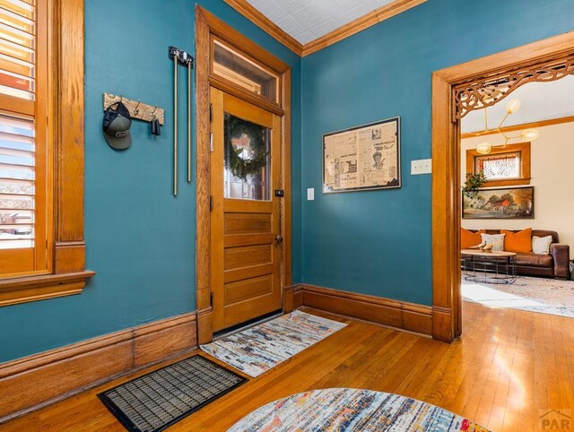 foyer entrance with baseboards, ornamental molding, and wood finished floors