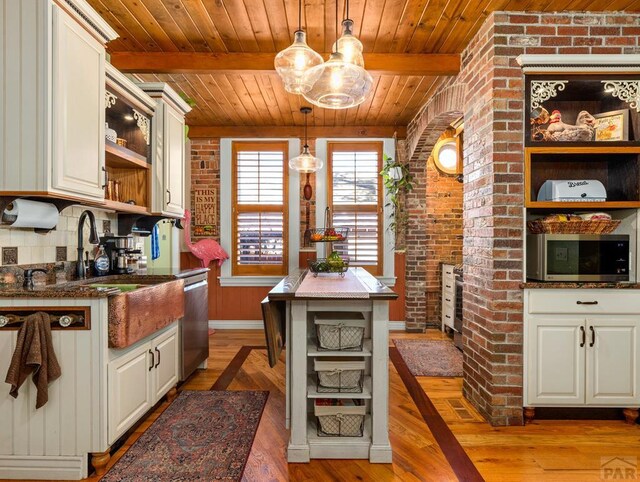 kitchen featuring brick wall, white cabinets, appliances with stainless steel finishes, open shelves, and decorative light fixtures