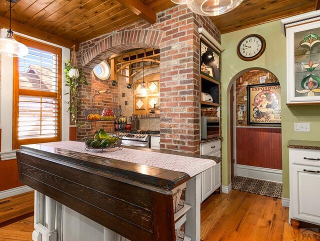 interior space with arched walkways, wooden ceiling, brick wall, light wood-type flooring, and beam ceiling