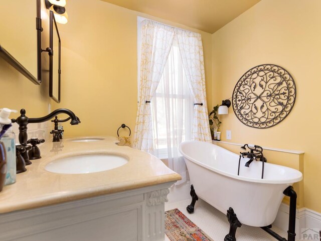 bathroom with a freestanding bath, a sink, and double vanity