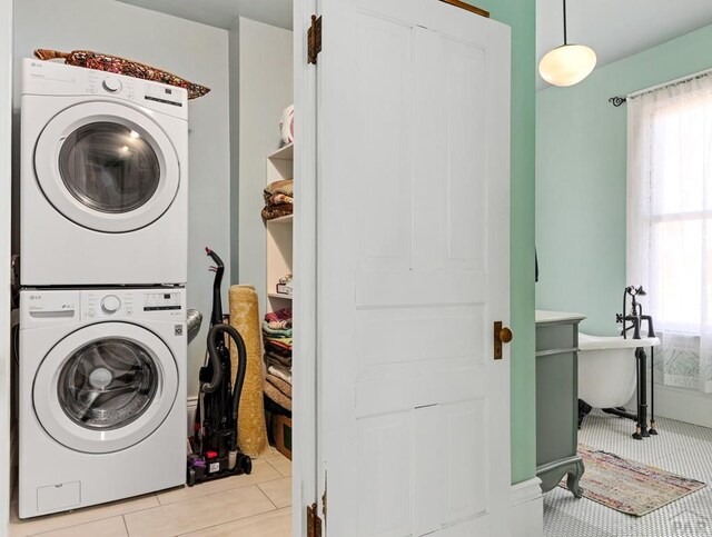 laundry area featuring stacked washer / drying machine, laundry area, and light tile patterned floors