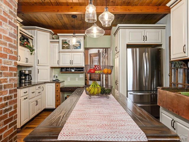 kitchen featuring hanging light fixtures, beam ceiling, glass insert cabinets, and freestanding refrigerator