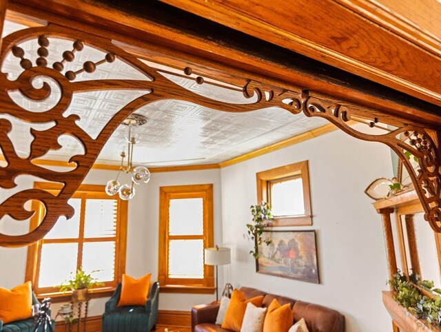 interior space featuring a chandelier, baseboards, an ornate ceiling, and crown molding