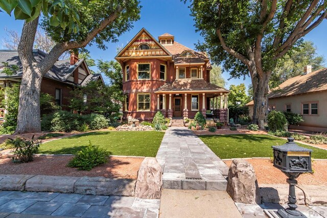 victorian home featuring covered porch and a front lawn