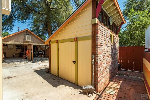 view of shed with a wall mounted air conditioner and fence