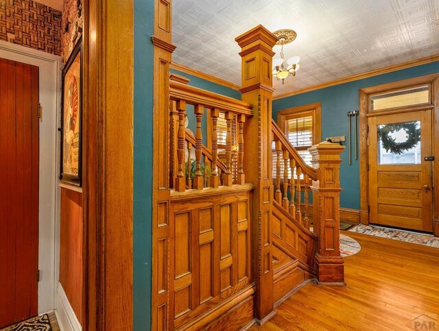 foyer with an ornate ceiling, stairway, ornamental molding, wood finished floors, and a notable chandelier