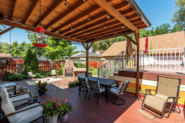 wooden terrace with a patio area, outdoor dining space, a fireplace, and fence