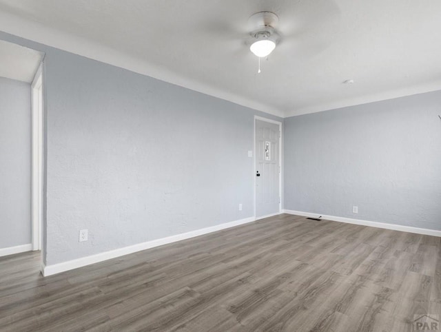 spare room featuring a ceiling fan, baseboards, and wood finished floors