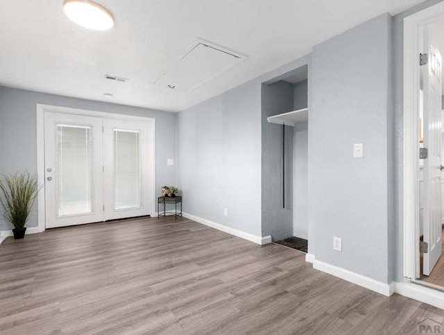 unfurnished bedroom featuring visible vents, attic access, light wood-style flooring, and baseboards