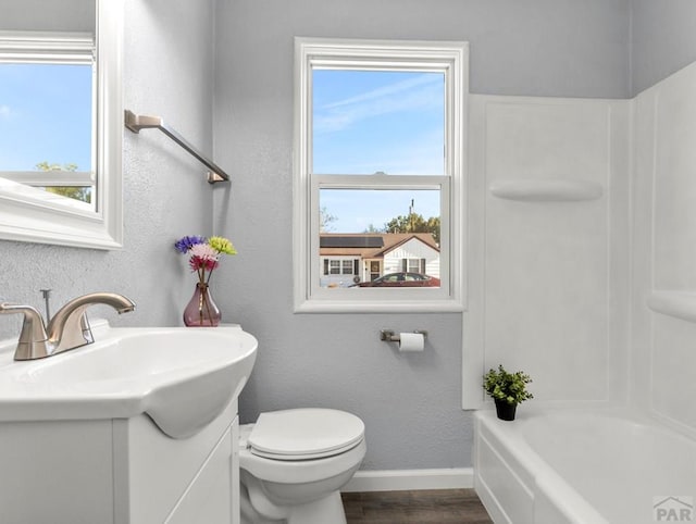 full bath with a textured wall, toilet, wood finished floors, vanity, and baseboards