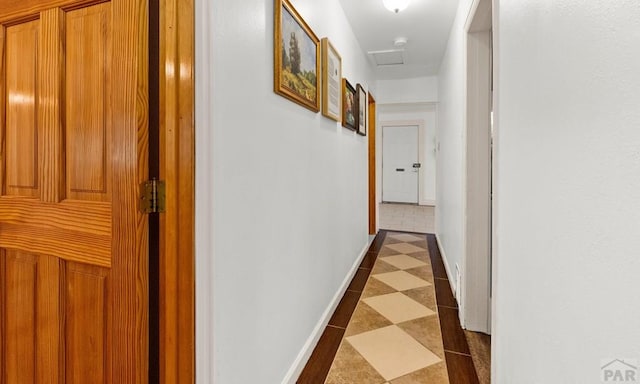 corridor with dark floors, attic access, and baseboards