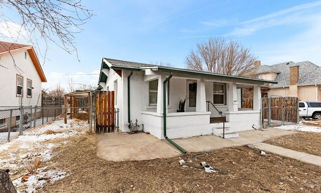 bungalow-style house with a porch, a gate, a fenced front yard, and stucco siding