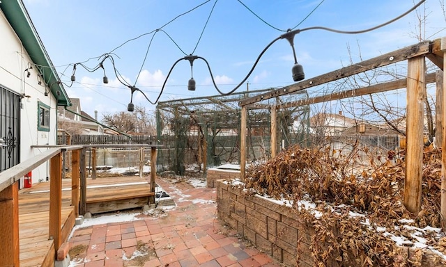 snow covered patio featuring fence and a wooden deck