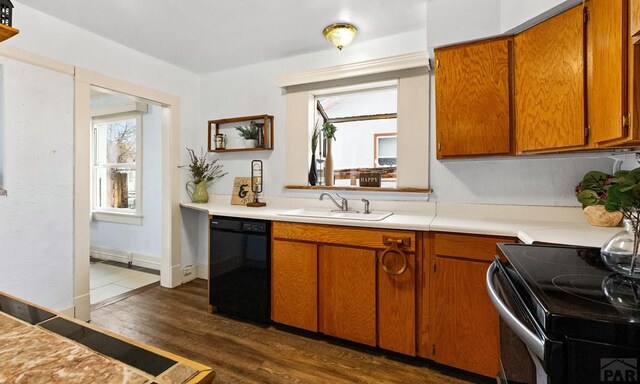 kitchen with black dishwasher, brown cabinets, dark wood finished floors, light countertops, and a sink