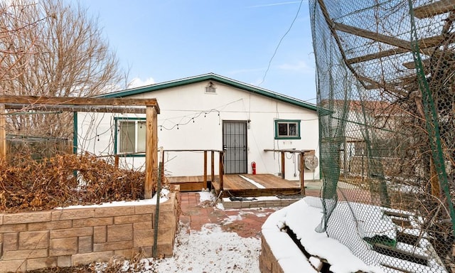 snow covered back of property featuring a wooden deck