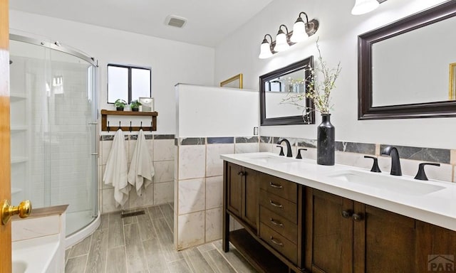 full bathroom featuring a stall shower, a sink, and tile walls