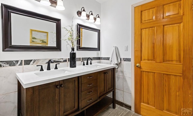 full bathroom with a wainscoted wall, a sink, tile walls, and double vanity