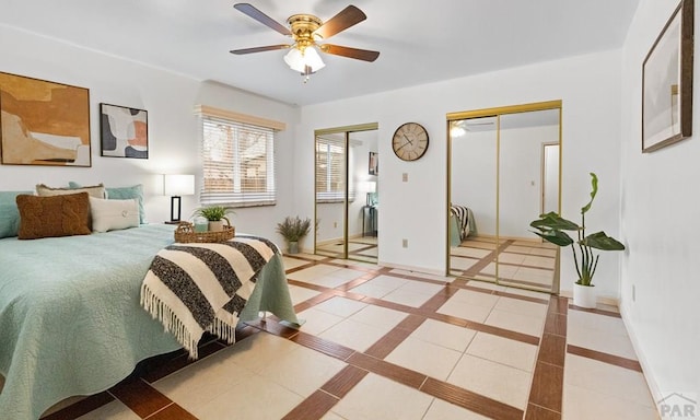 tiled bedroom with a ceiling fan, baseboards, and two closets