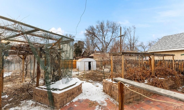 yard layered in snow with a storage shed, a fenced backyard, and an outbuilding