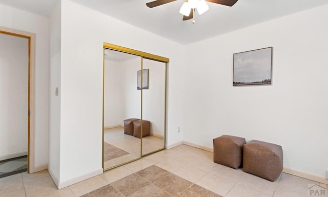 bedroom featuring light tile patterned floors, a ceiling fan, baseboards, and a closet