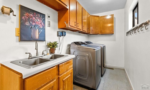 washroom with washer and clothes dryer, a sink, cabinet space, and baseboards