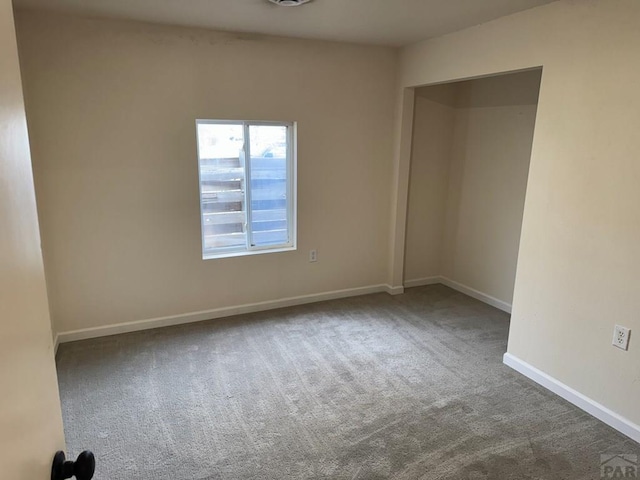 carpeted spare room featuring baseboards