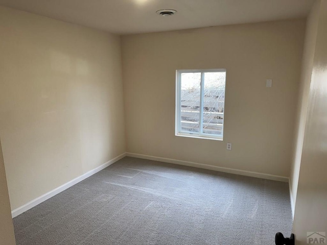 empty room featuring carpet floors, visible vents, and baseboards