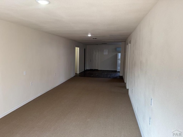 hallway featuring light carpet and baseboards