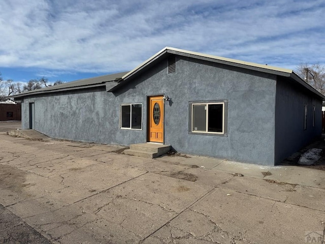 back of property with a patio and stucco siding