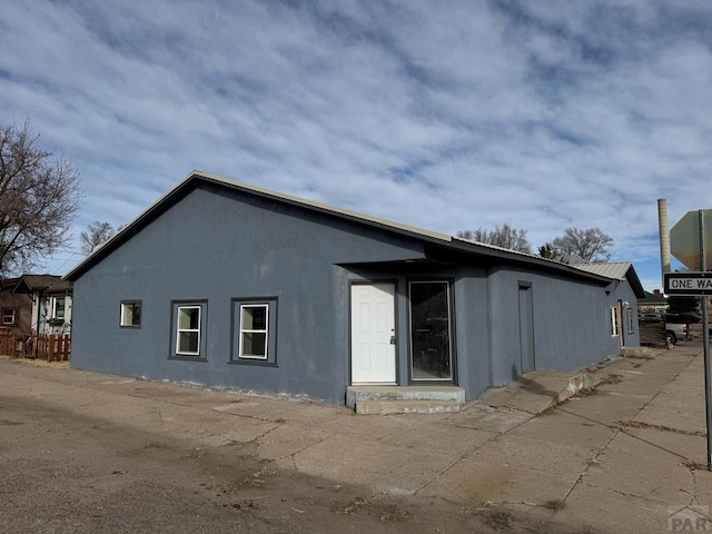 rear view of property with entry steps and stucco siding