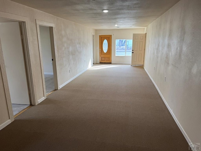 corridor with baseboards and light colored carpet