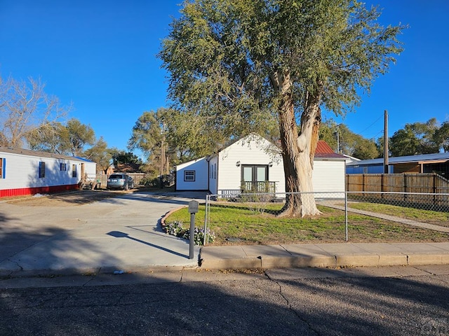 view of front of house featuring fence, driveway, and a front lawn